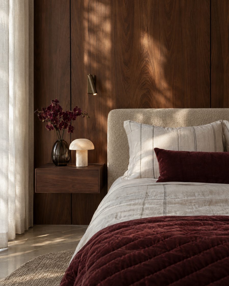 Visualisation: a walnut bedside with an alabaster lamp and burgundy velvet bedding