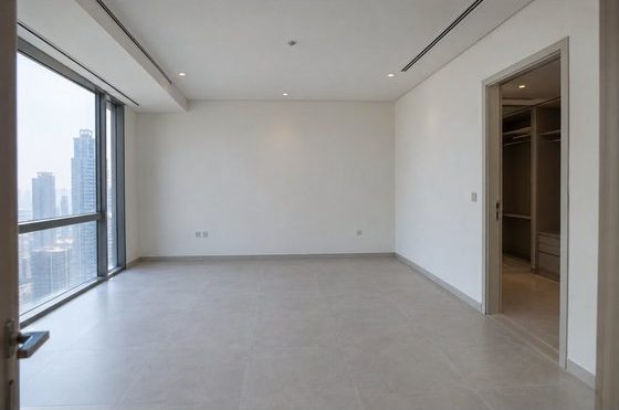 The bedroom at handover: empty, with white walls and a window onto the city