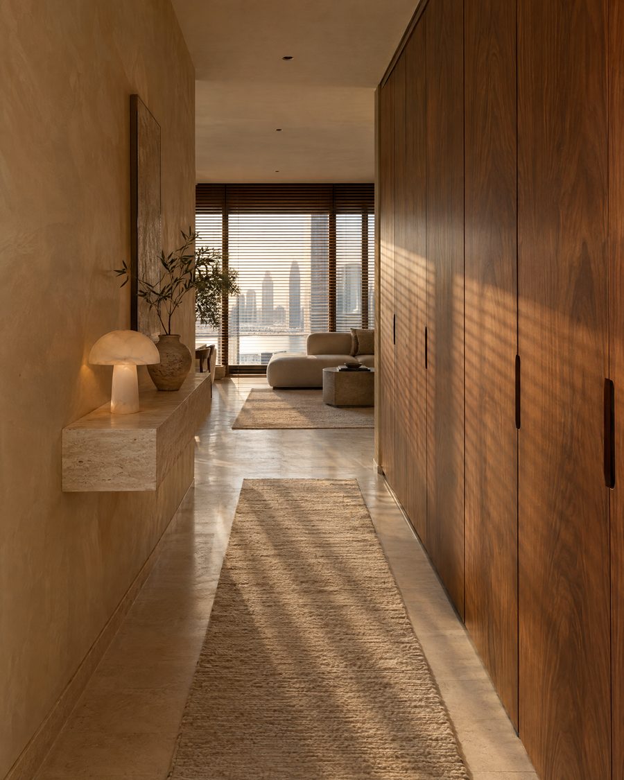 Visualisation: the hallway, with walnut wardrobes, soft beige limewash and an alabaster lamp on a travertine shelf