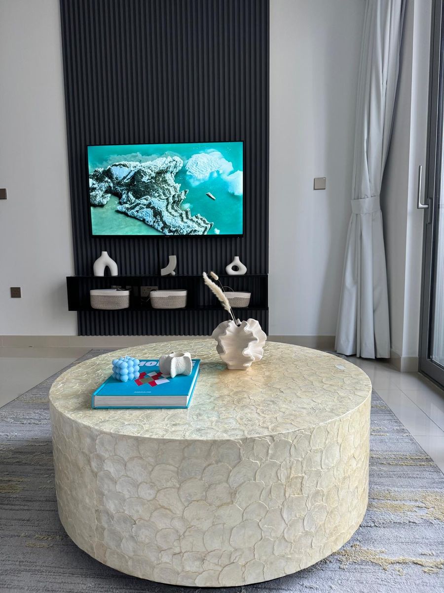 The TV wall after: styled shelves and a capiz shell coffee table