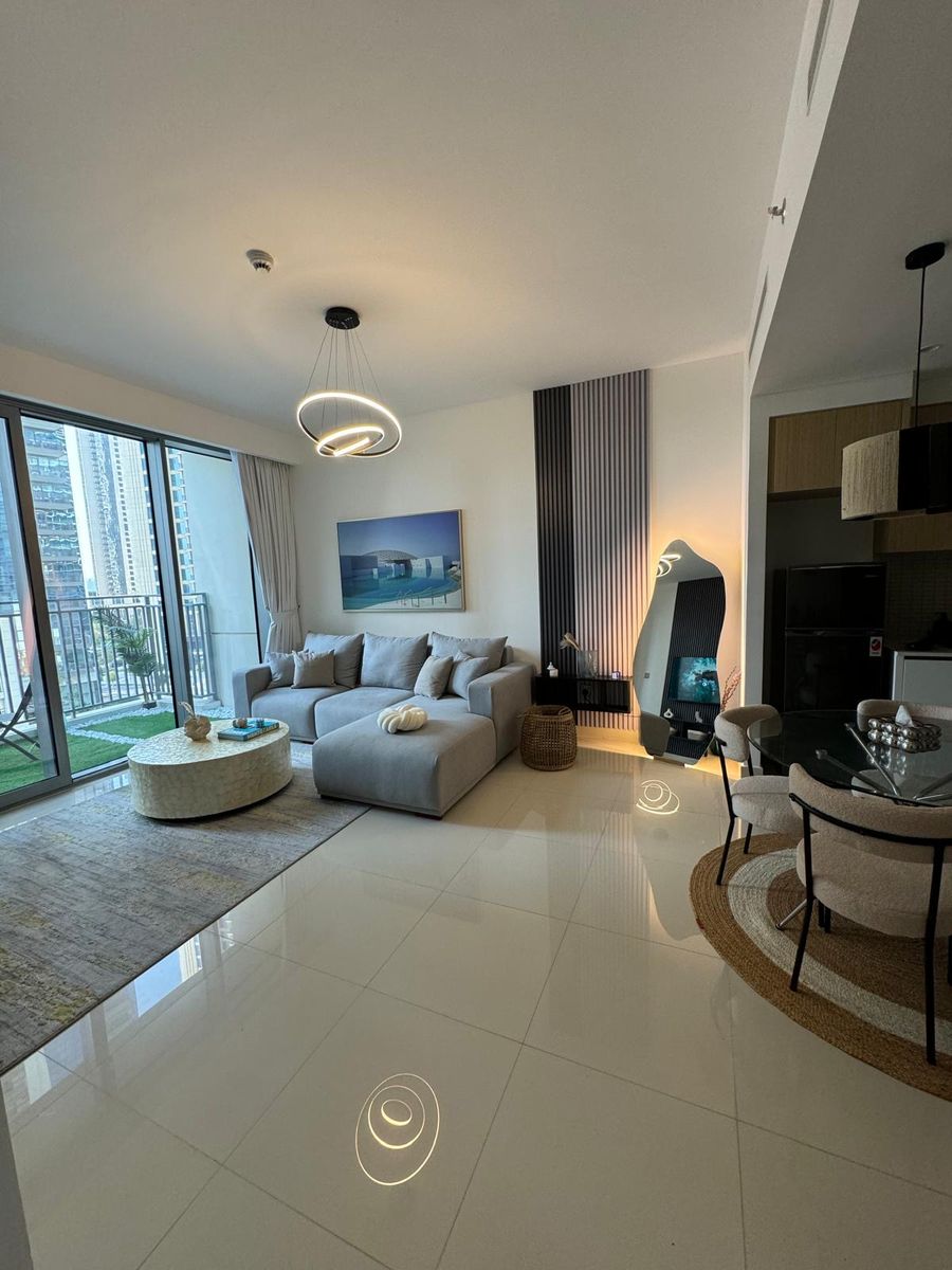 The living room after: a grey chaise sofa, a capiz shell coffee table and a sculptural ring pendant