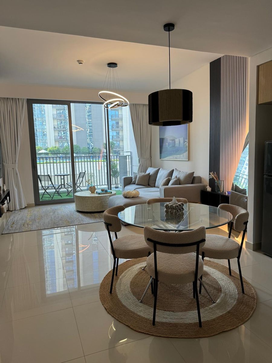 Bouclé dining chairs around a glass table on a round jute rug, with the living room beyond