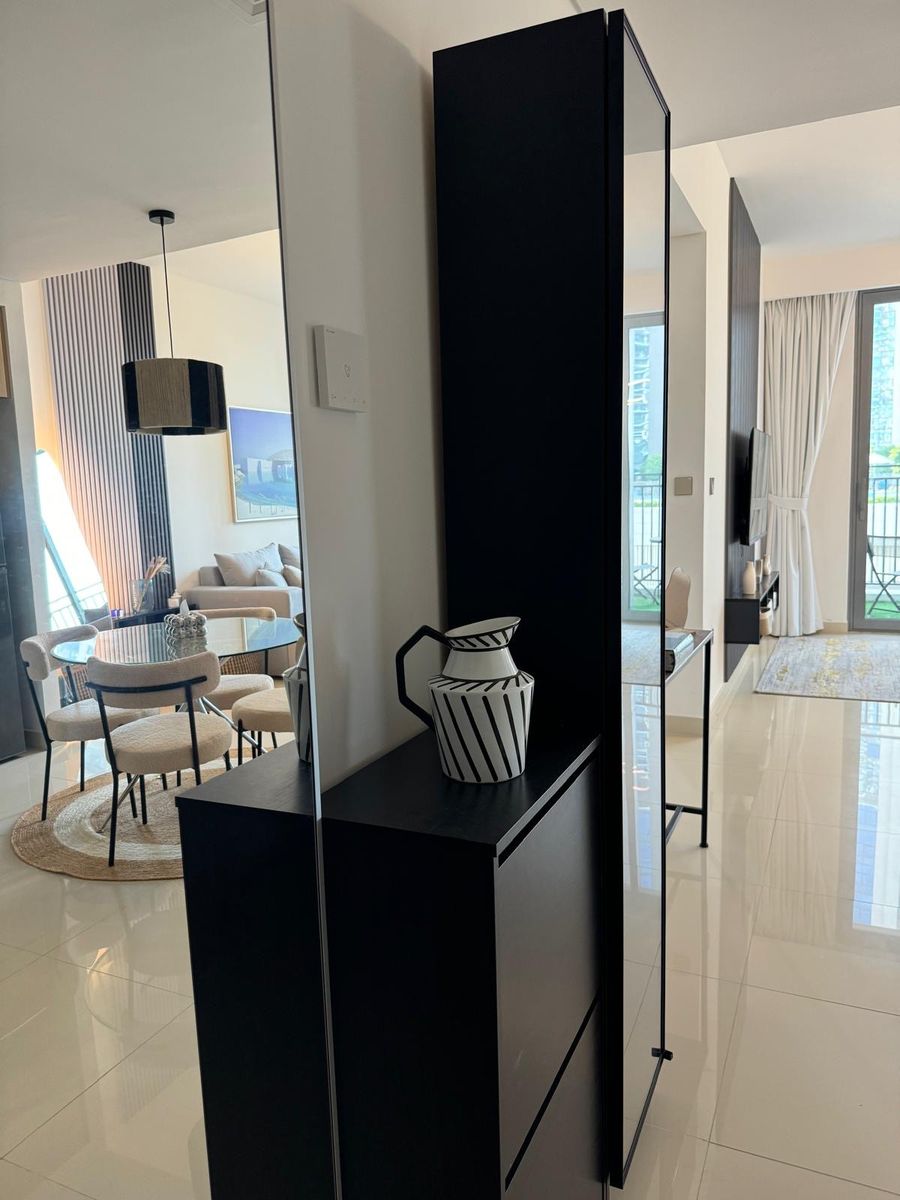 Entrance cabinet with a striped vase and a full-height mirror, looking into the dining area