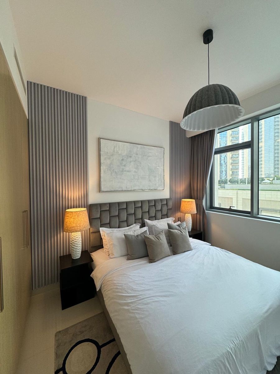 The bedroom after: ceramic lamps, a pleated dome pendant and neutral bedding