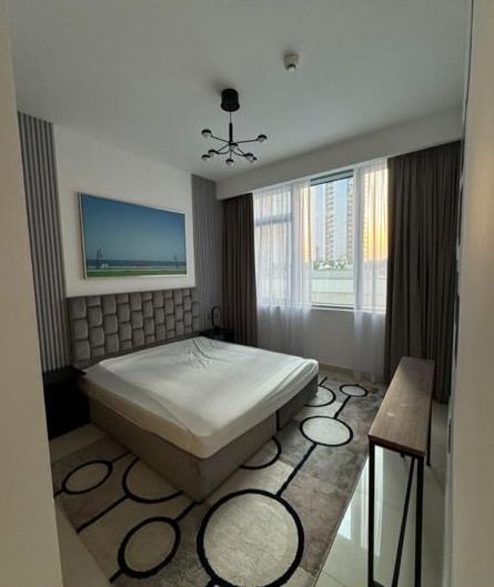 The bedroom before, with a black chandelier and an unmade bed