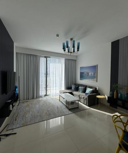 The living room before, with a dated chandelier, a dark sofa and a yellow chair