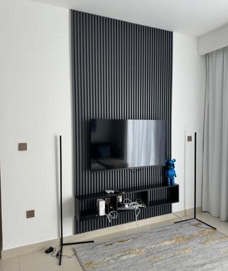 The TV wall before: a bare console with cables and two floor lamps