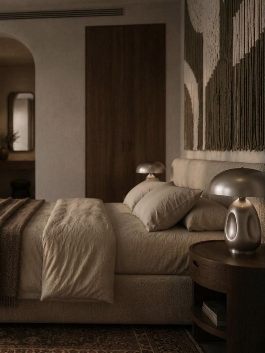Bedside with a sculptural metal lamp and a macramé wall hanging