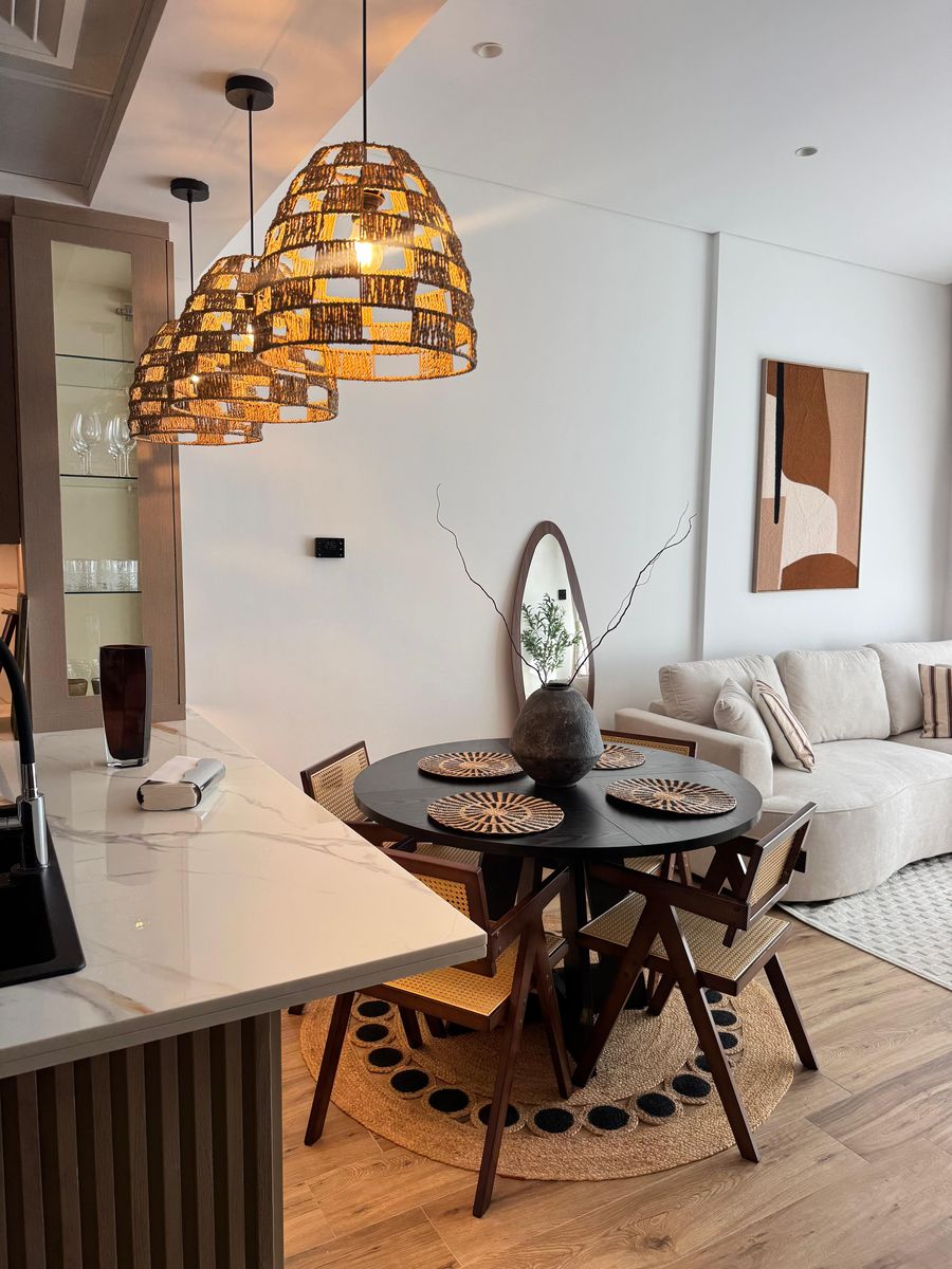Woven pendants over a round black dining table with cane-back chairs