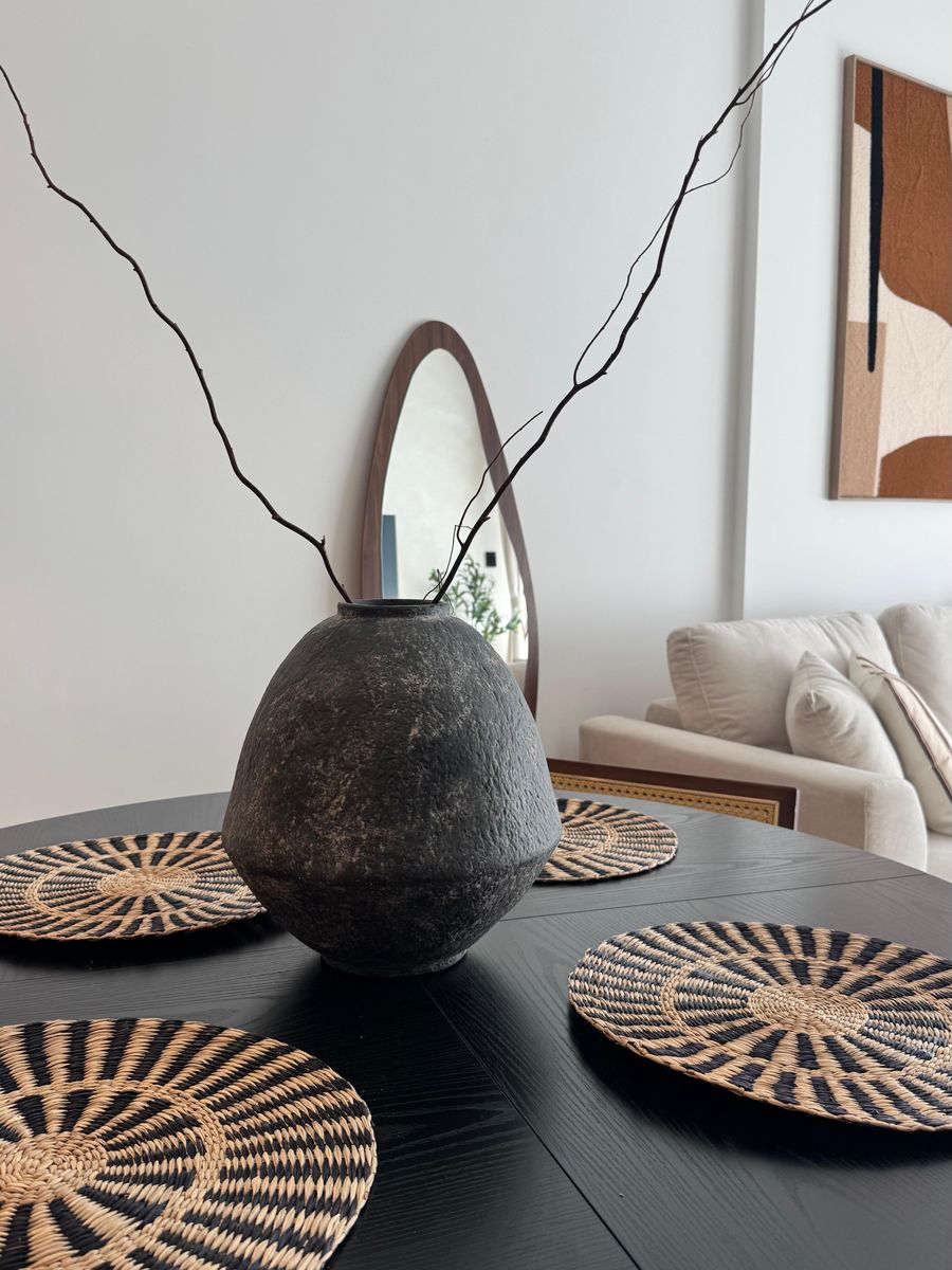 Stone vase with branches on the dining table, with woven placemats