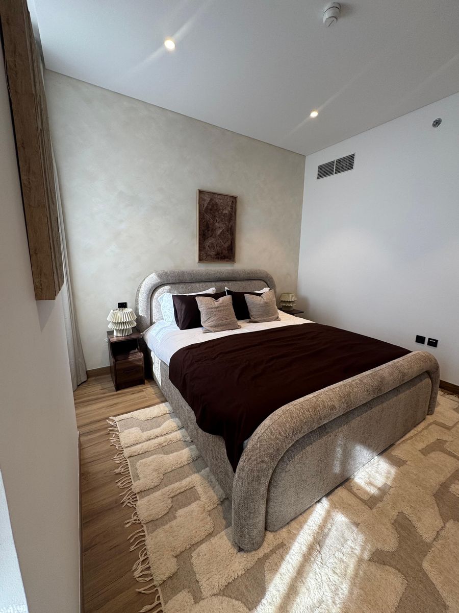 Bedroom with a textured rug and an artwork above the bed