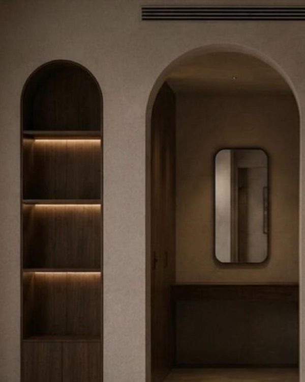 Arched niche with lit walnut shelves beside an arched doorway