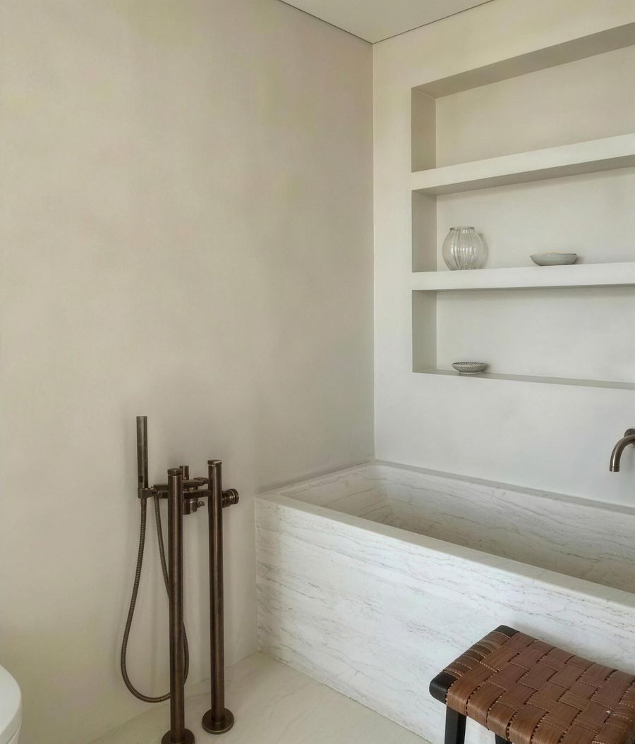The bathroom after: a stone-clad bath with brushed bronze fittings and built-in shelves