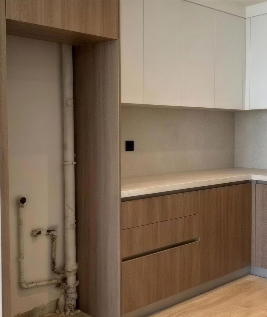 The kitchen at handover, with exposed pipes beside the units