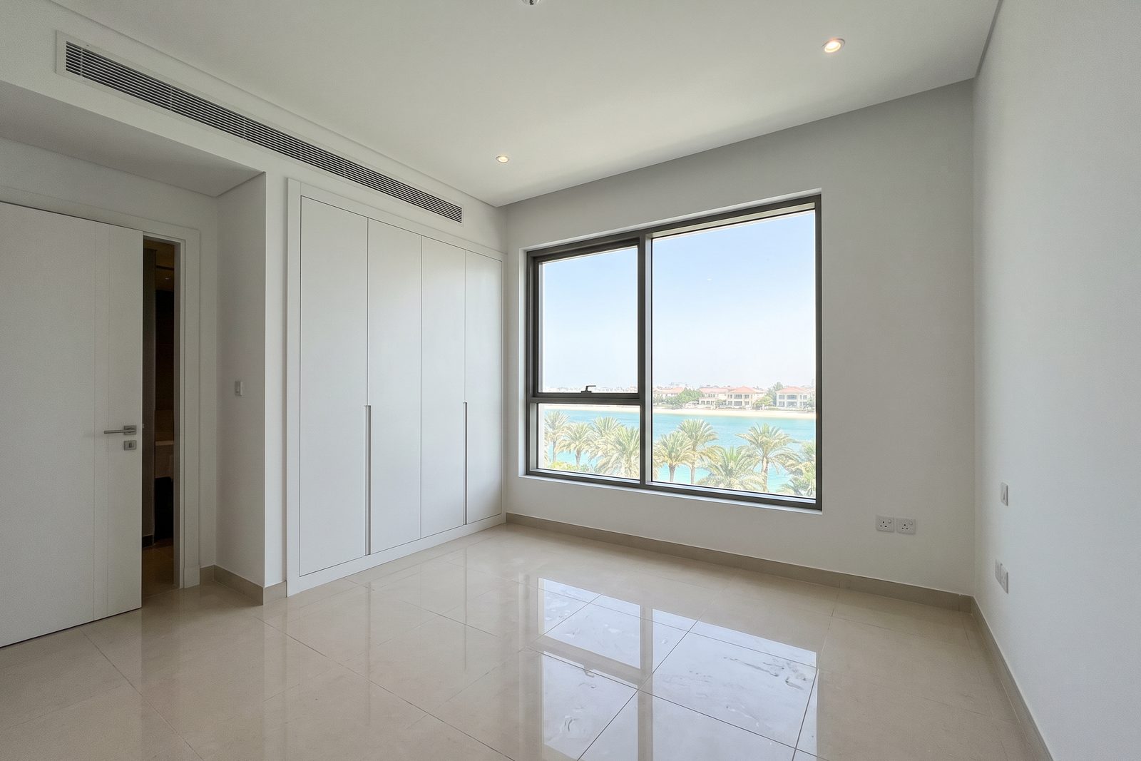 Visualisation: the bedroom of a typical Palm Jumeirah apartment at handover, empty, with built-in wardrobes and a sea view