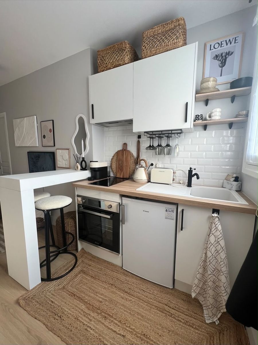 The kitchen after: open oak shelves, a glass rack, a bar counter with bouclé stools and styled walls
