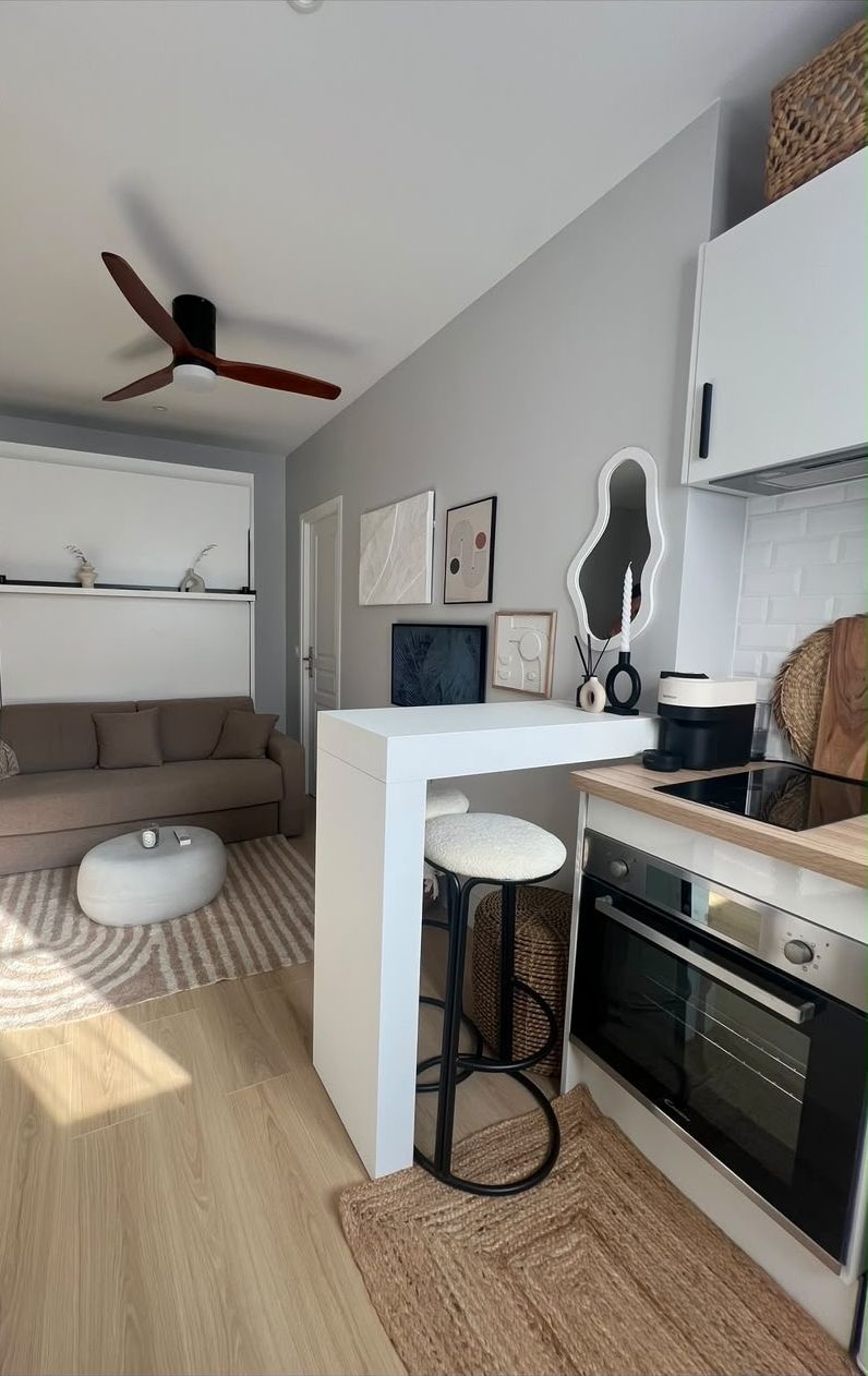 The living room after: a sofa under a wall bed with its shelf, a striped rug and a bar counter