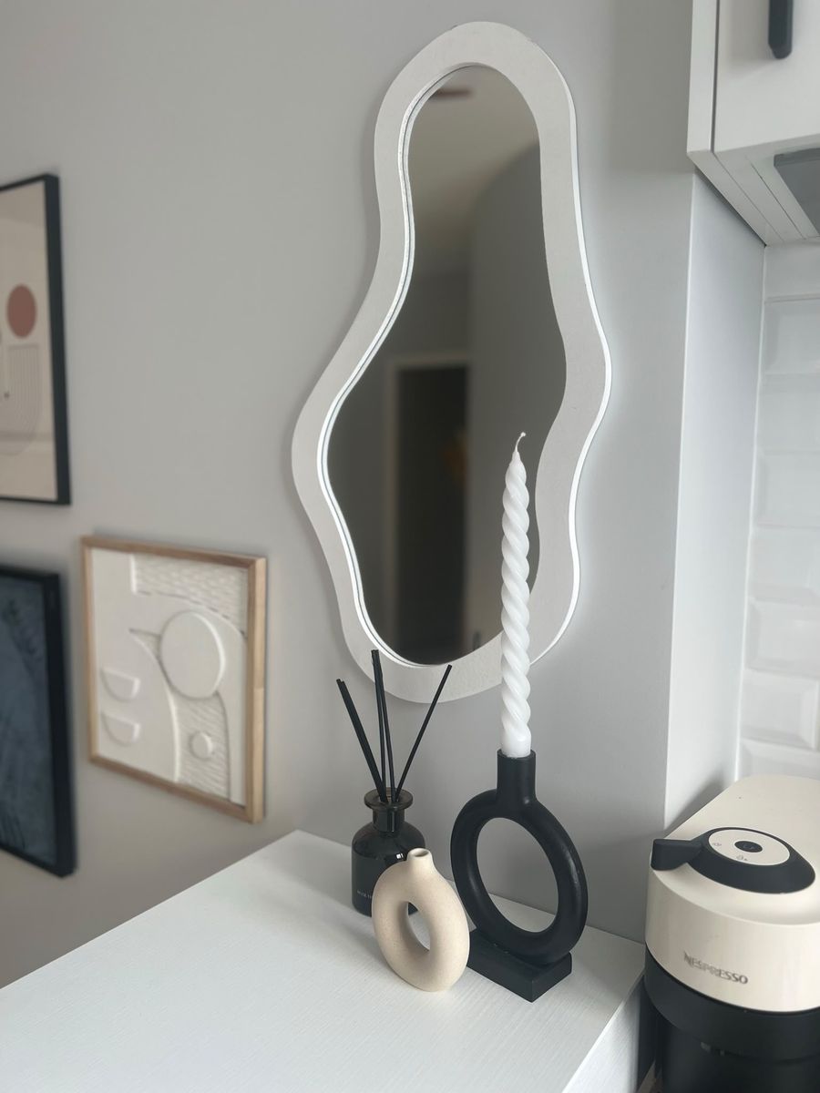 A wavy white mirror, a twisted candle and a ring candle holder