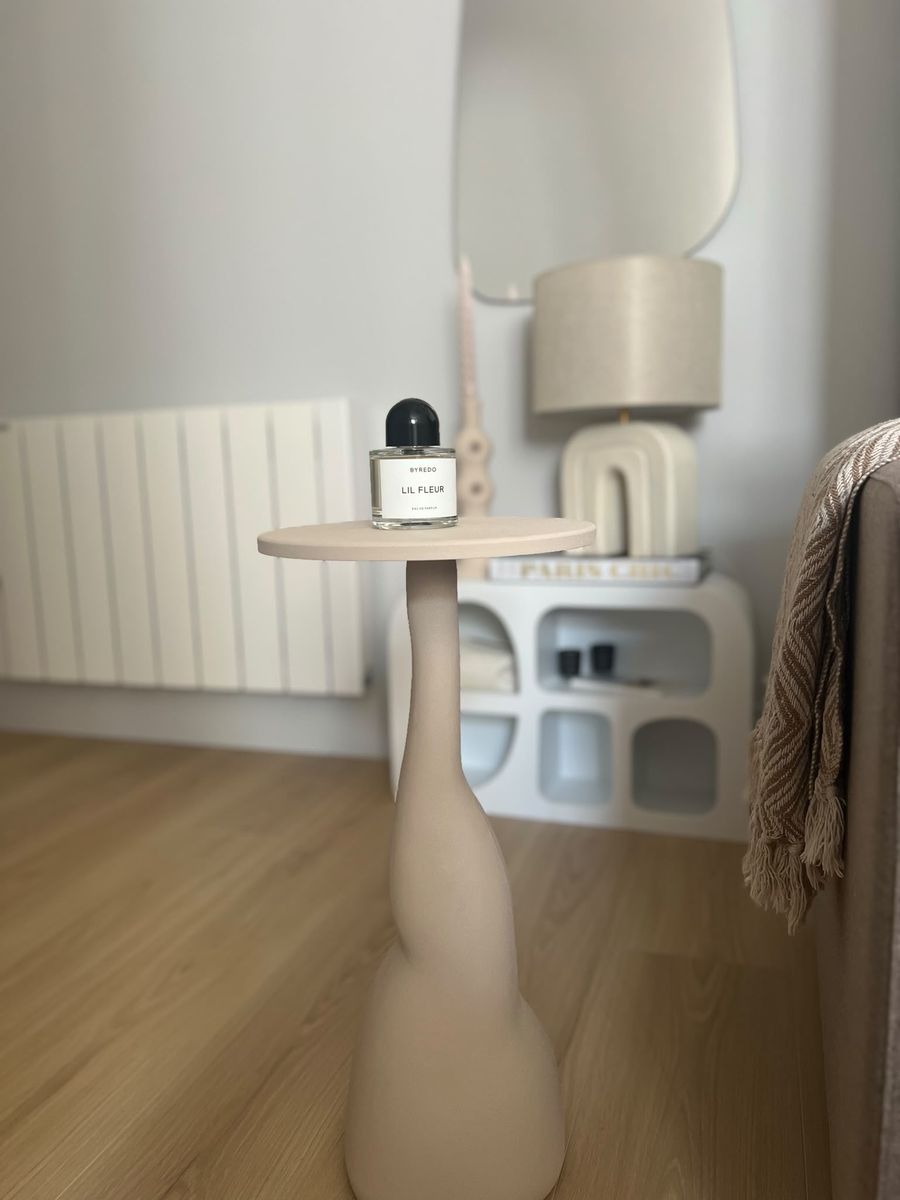 A sculpted side table in front of the sideboard and lamp