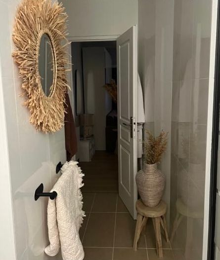 The bathroom entrance after: a raffia mirror, a towel rail and a woven vase