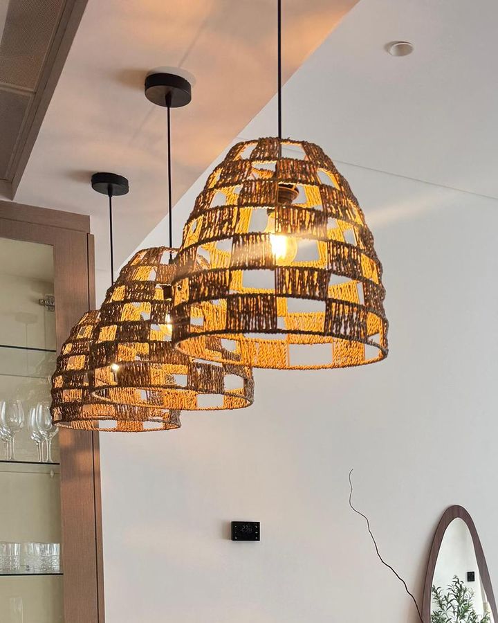 Three woven pendants hanging over the dining table in the JVC apartment